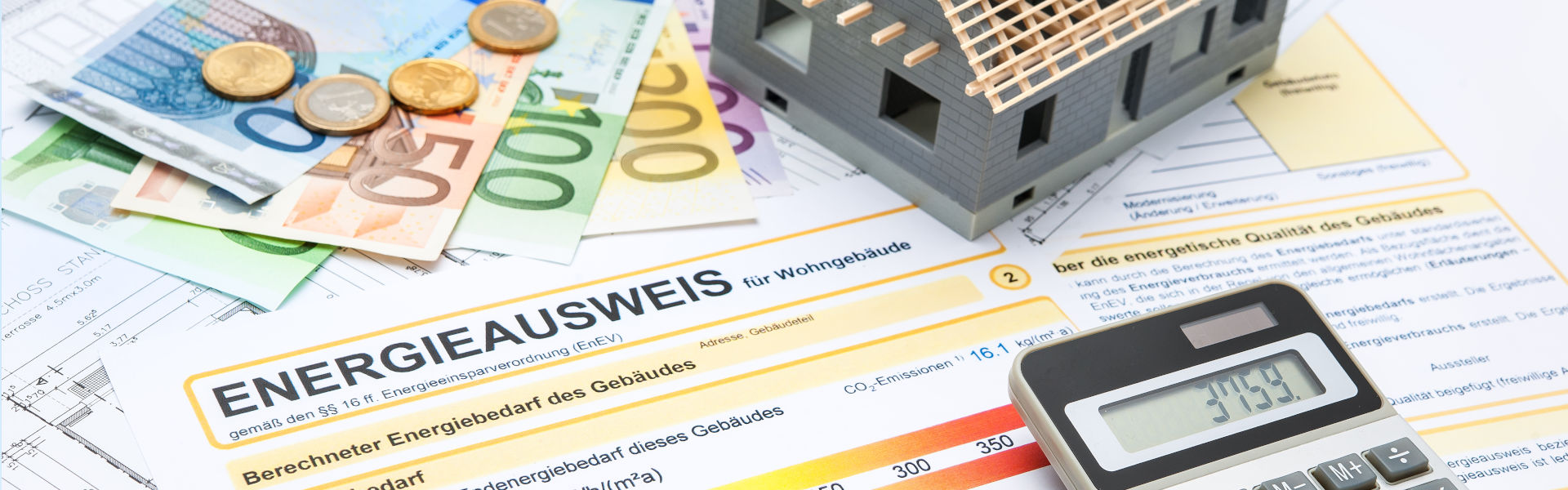 Energieausweis und Betriebskostenabrechnung auf einem Tisch mit Geld, einem Taschenrechner und einem Modellhaus - HWA-Frenzel